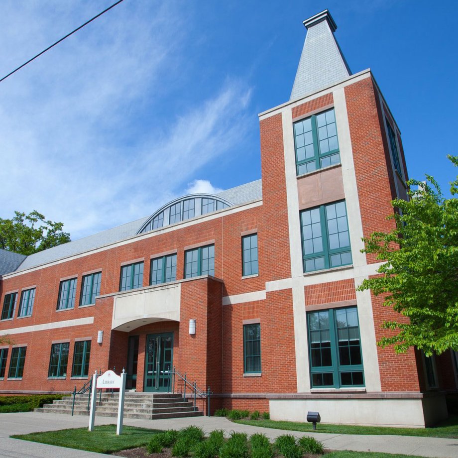 Exterior image of the Bloomfield Campus Library framed by green trees and blue sky