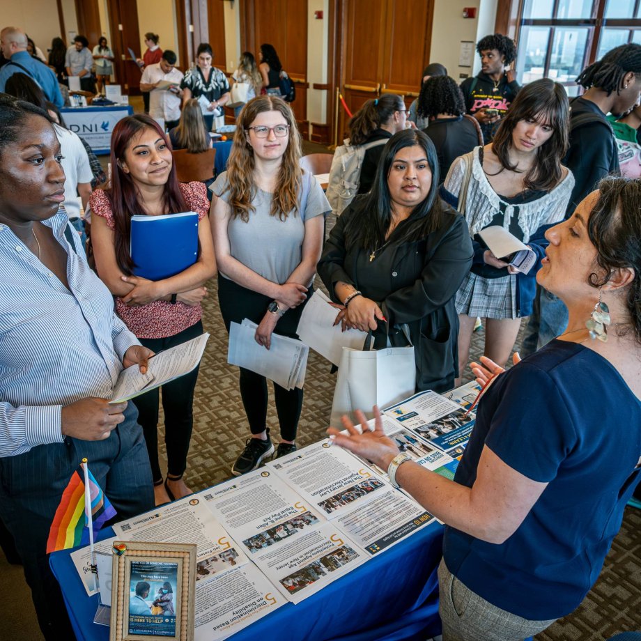 A recruiter speaks to a group of college students at a career fair