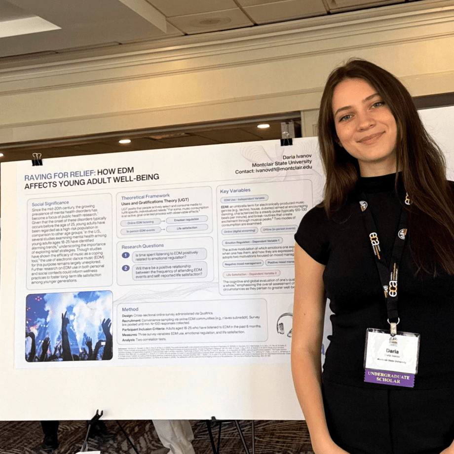 Student stands in front of her research project on display.