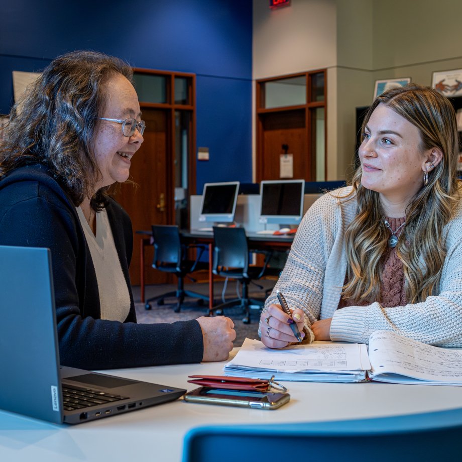 Student and professor sitting at table with textbooks