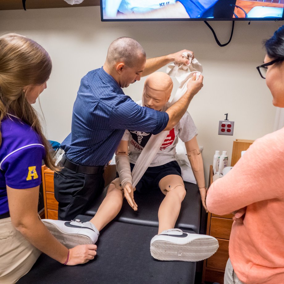 Students practice athletic training techniques in the lab. 