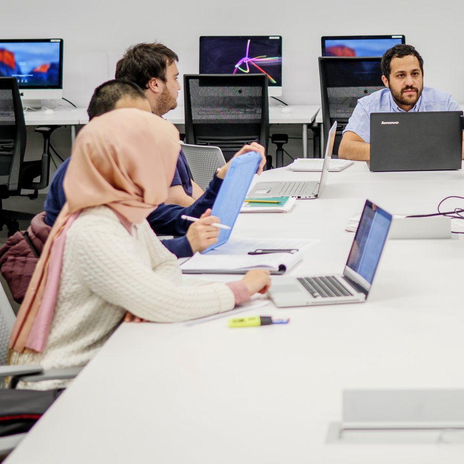 Students working on their computers at a long table.