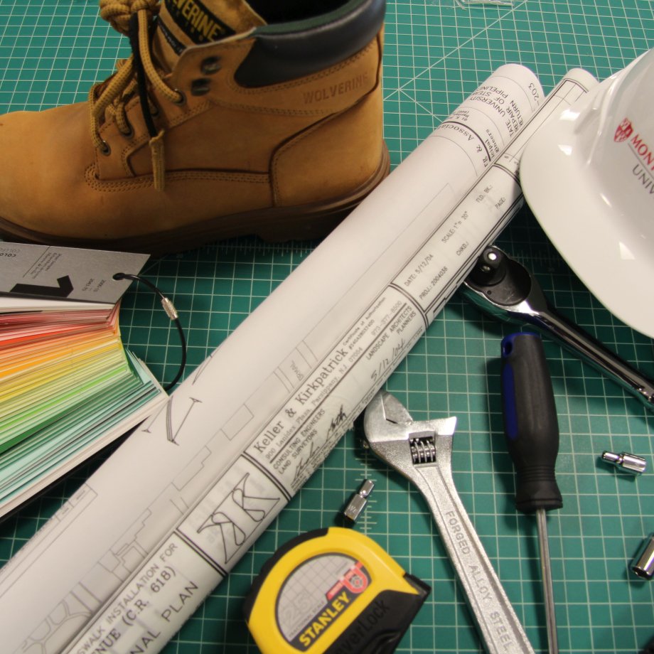 Photo of a hard hat, boot, paint samples, construction drawings and various maintenance tools