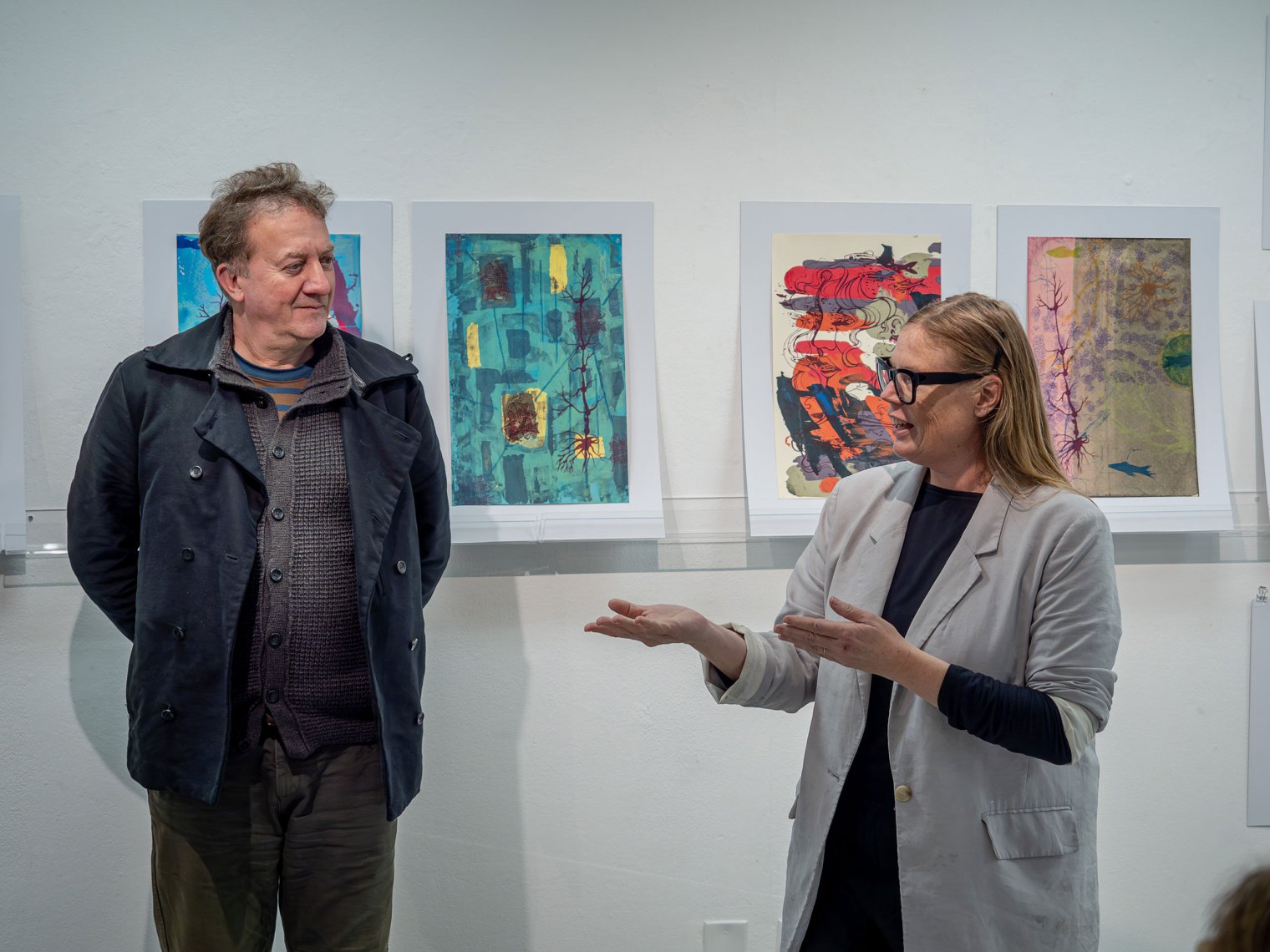 Thomas Mueller and Jennifer Wroblewsk stand before student artwork.