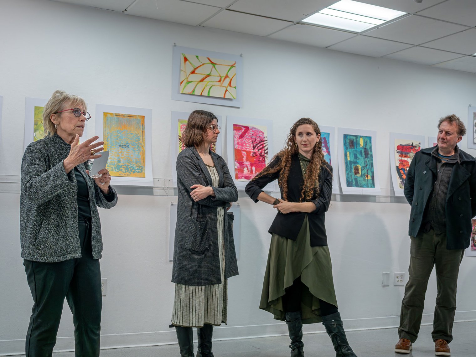 Professors Cathy Bebout, Bridget McGuire, Sharon Lindenfeld and Thomas Mueller stand before a student art display.