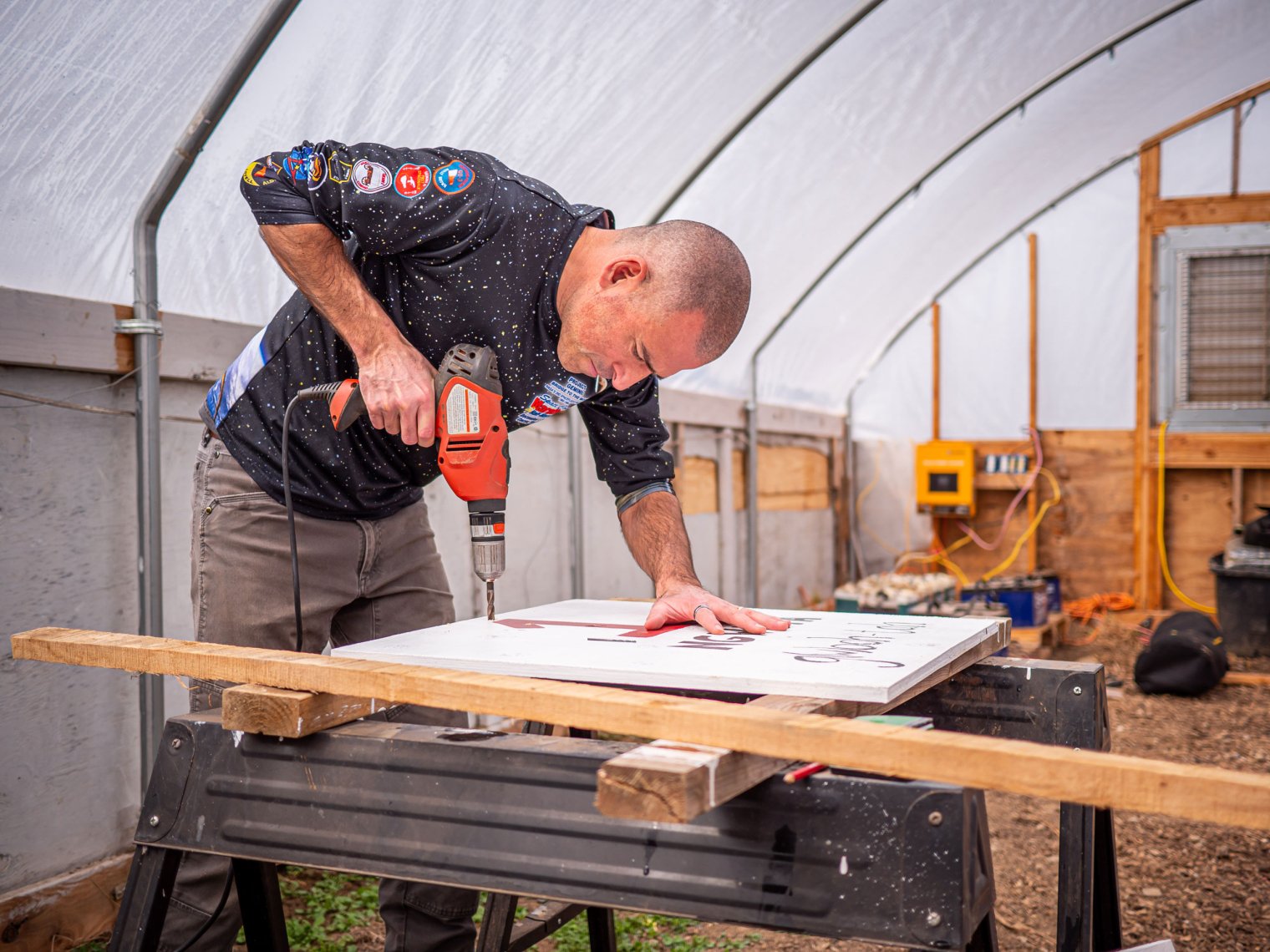 Man uses drill on sign.
