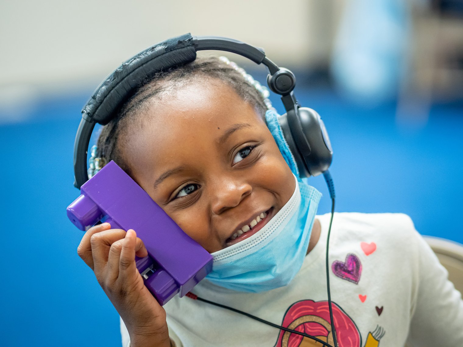 young child holding block while wearing headphones