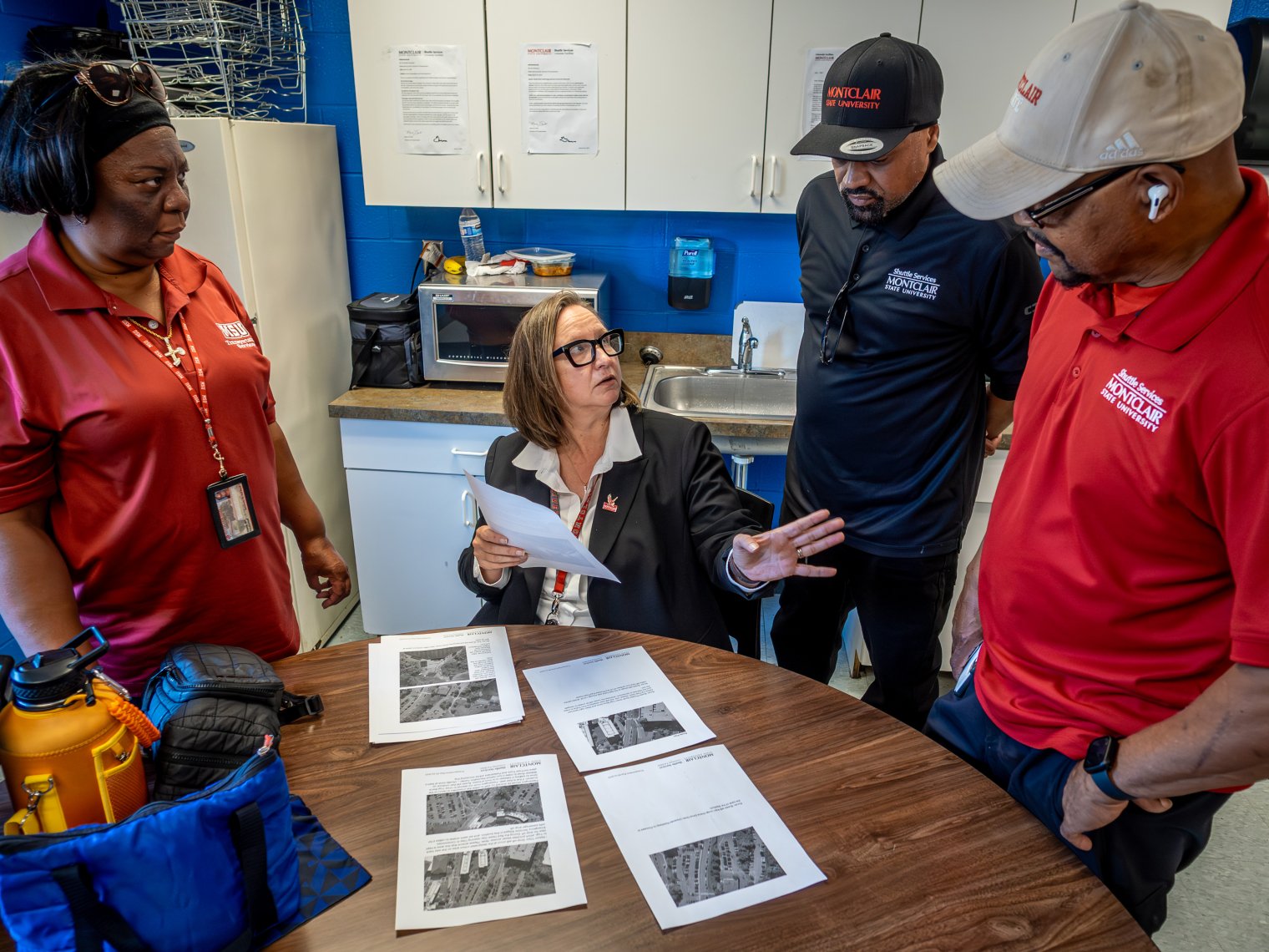 Monica sitting down explaining a group of photos to other employees.