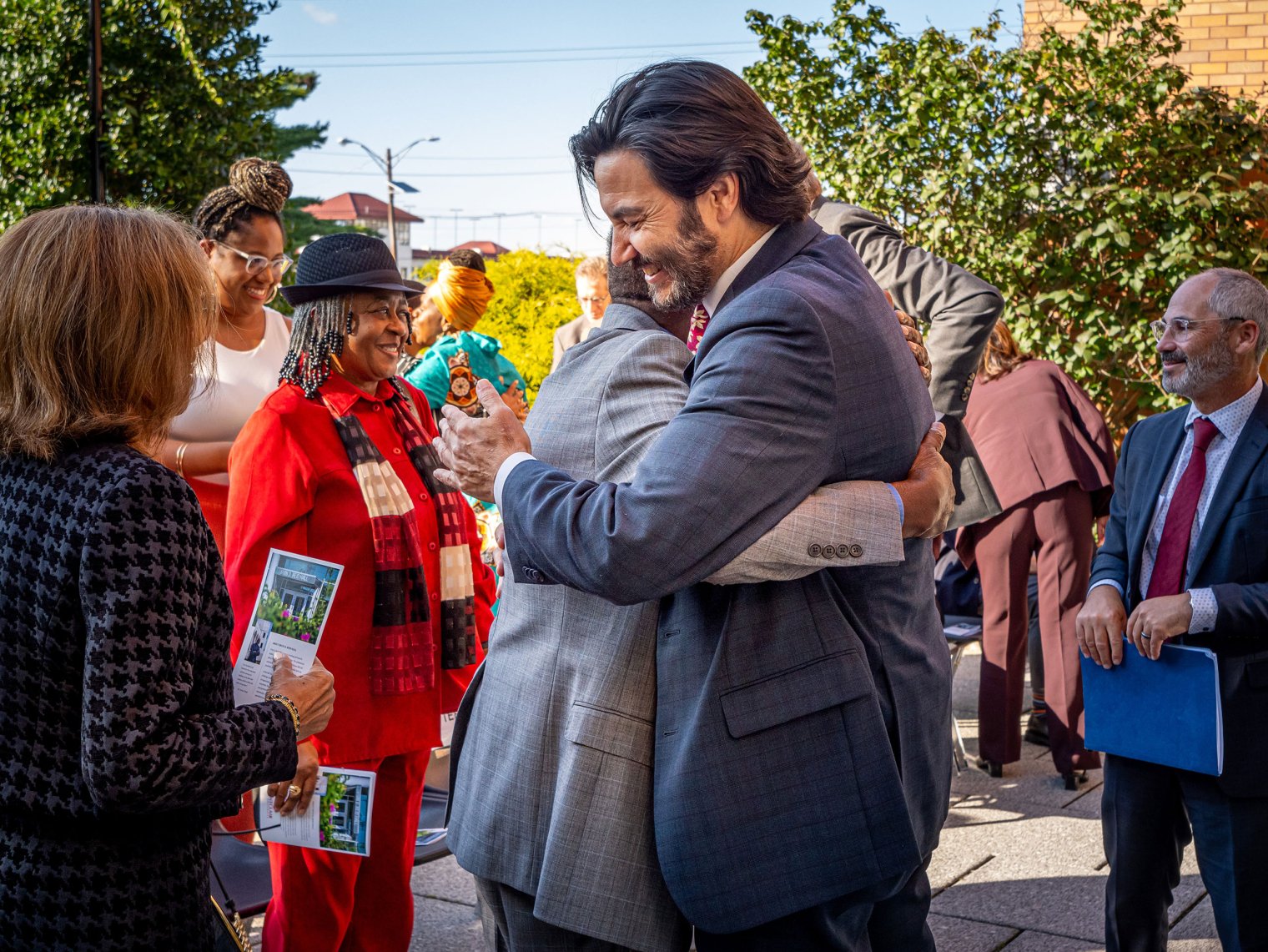 Two men embrace, celebrating the renaming of the building.