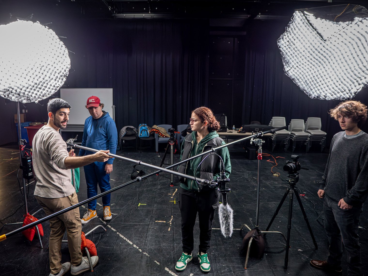 Stage crew with lights and boom mics set up for the video shoot.