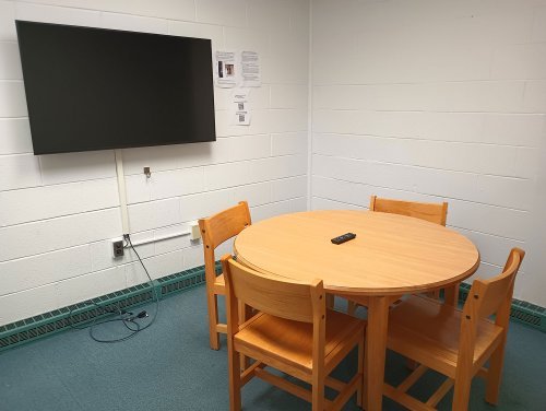A desk with 4 chairs and a monitor