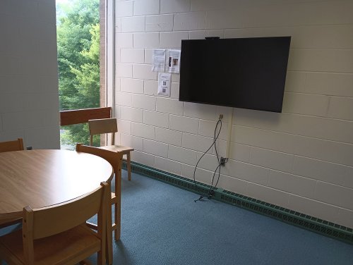 A desk with 4 chairs and a monitor