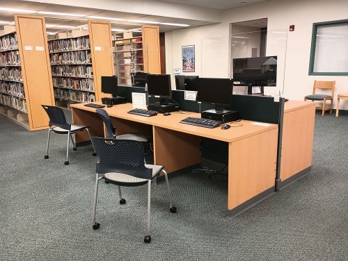 Several computers with book stacks in the background