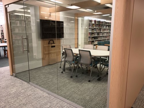 a glass window study pod with conference table and monitor 