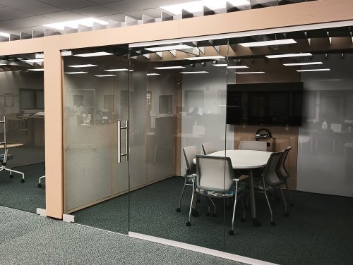 a glass window study pod with conference table and monitor 