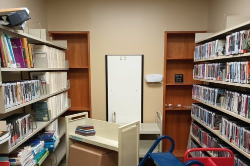 room with shelves of DVDs, a whiteboard and a cart