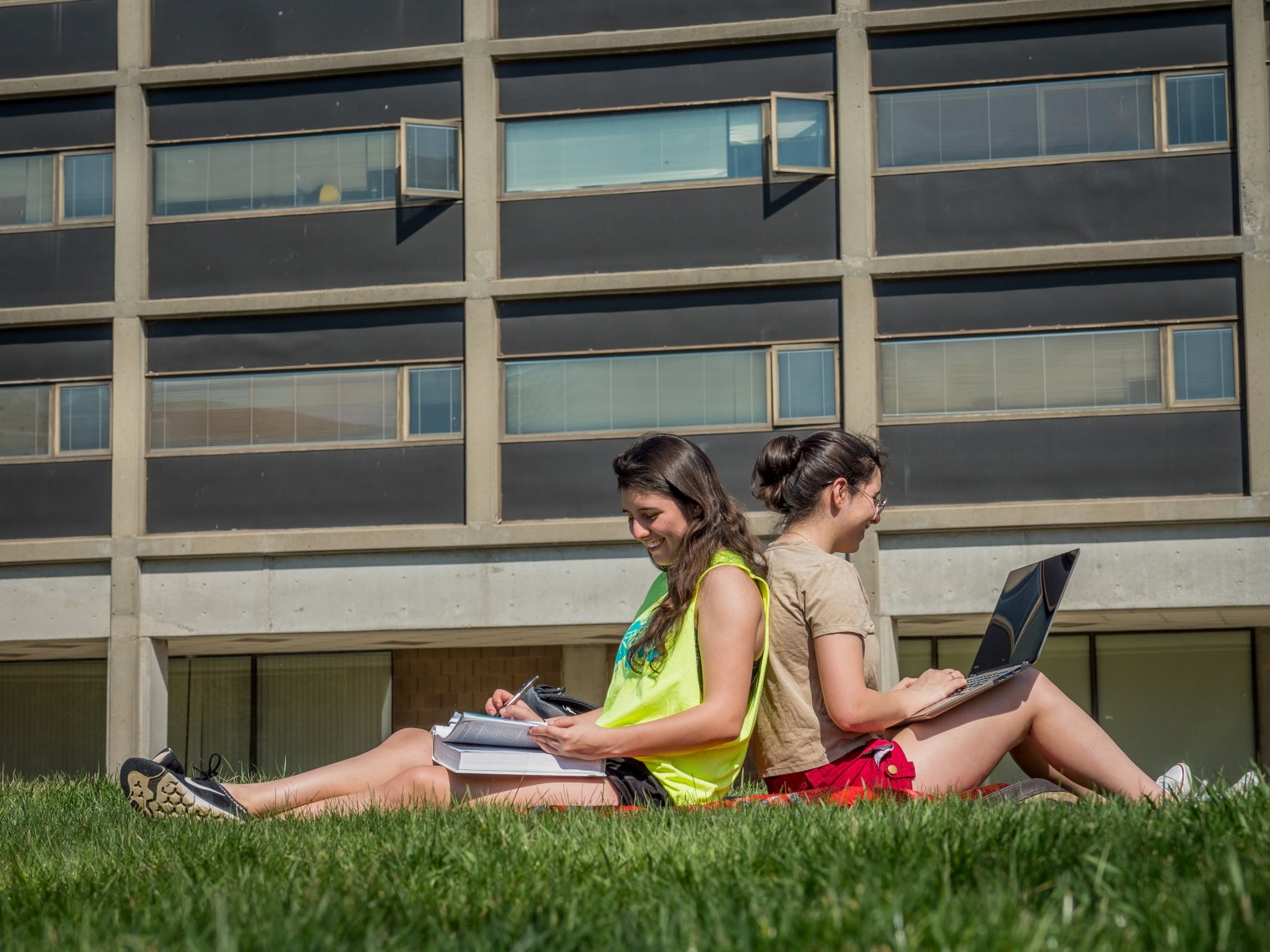 two students studying back to back outside