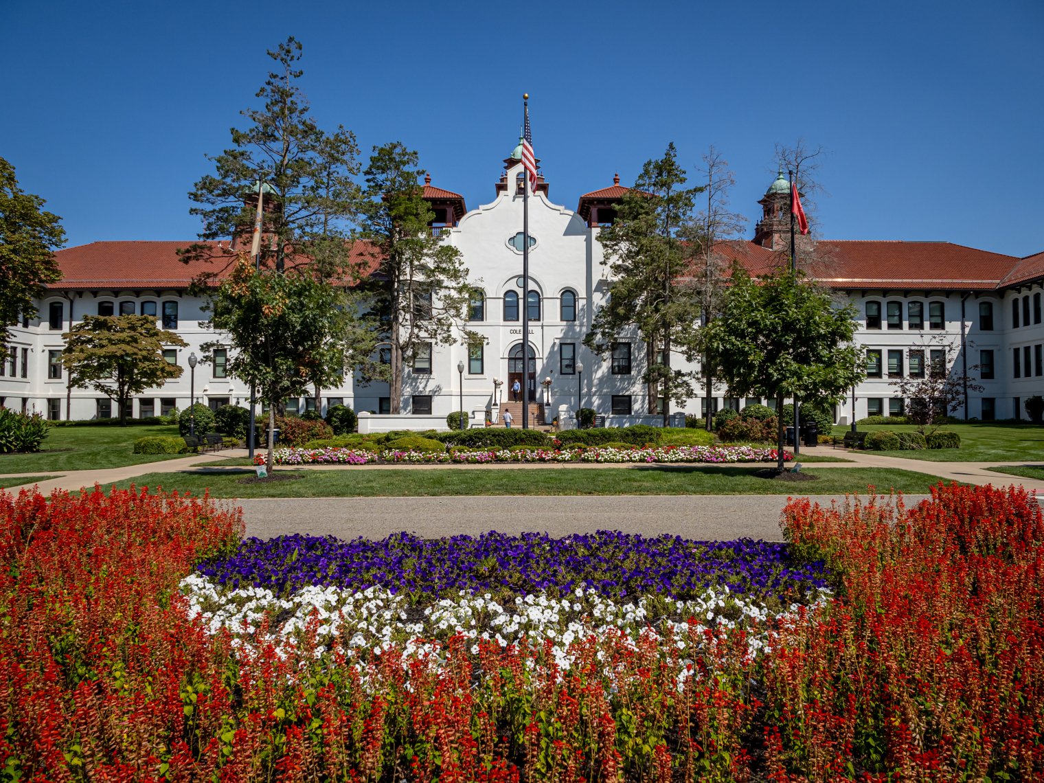 A picture of Cole Hall surrounded by flowers & trees.