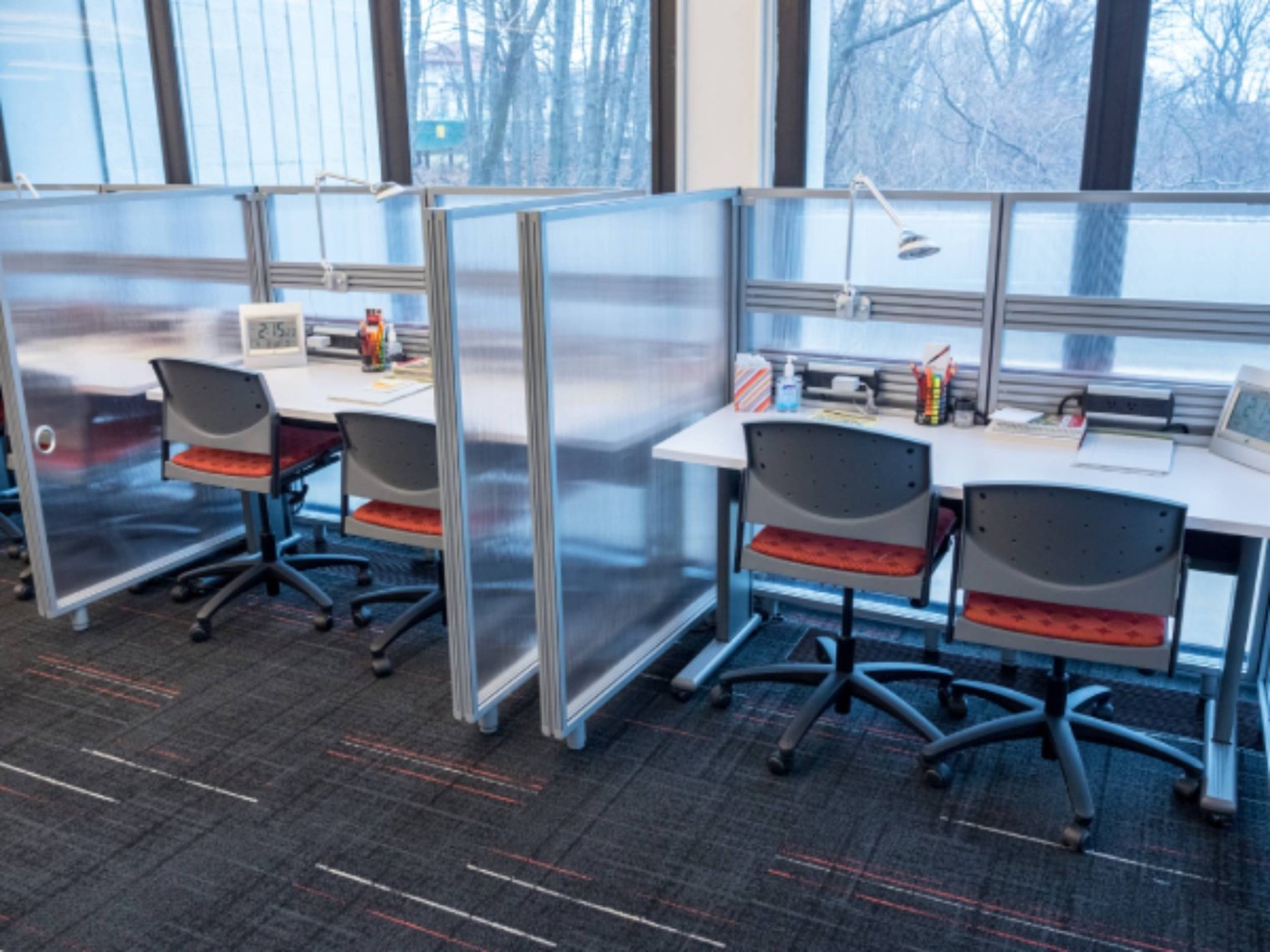 Two cubicles each with two chairs, in a modern office setting