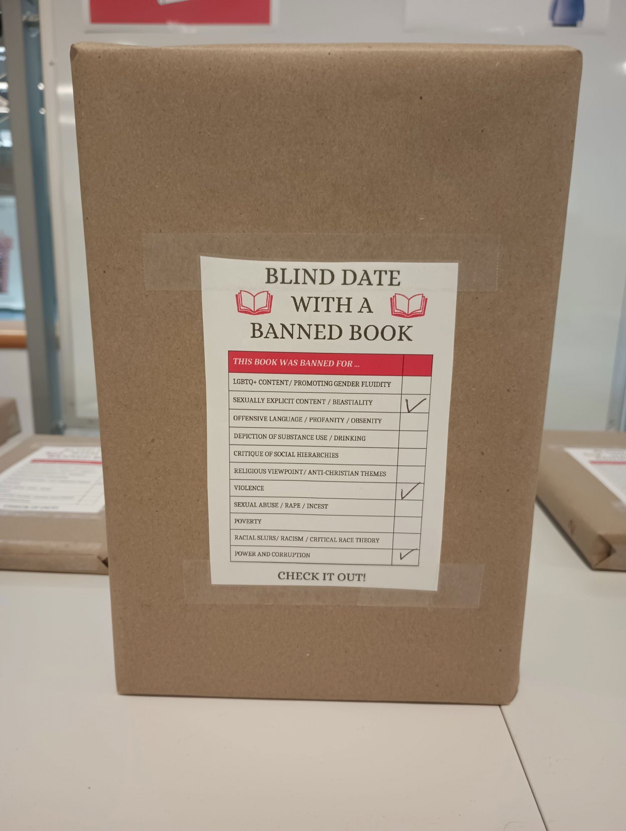 a wrapped banned book with a label stating why its's banned