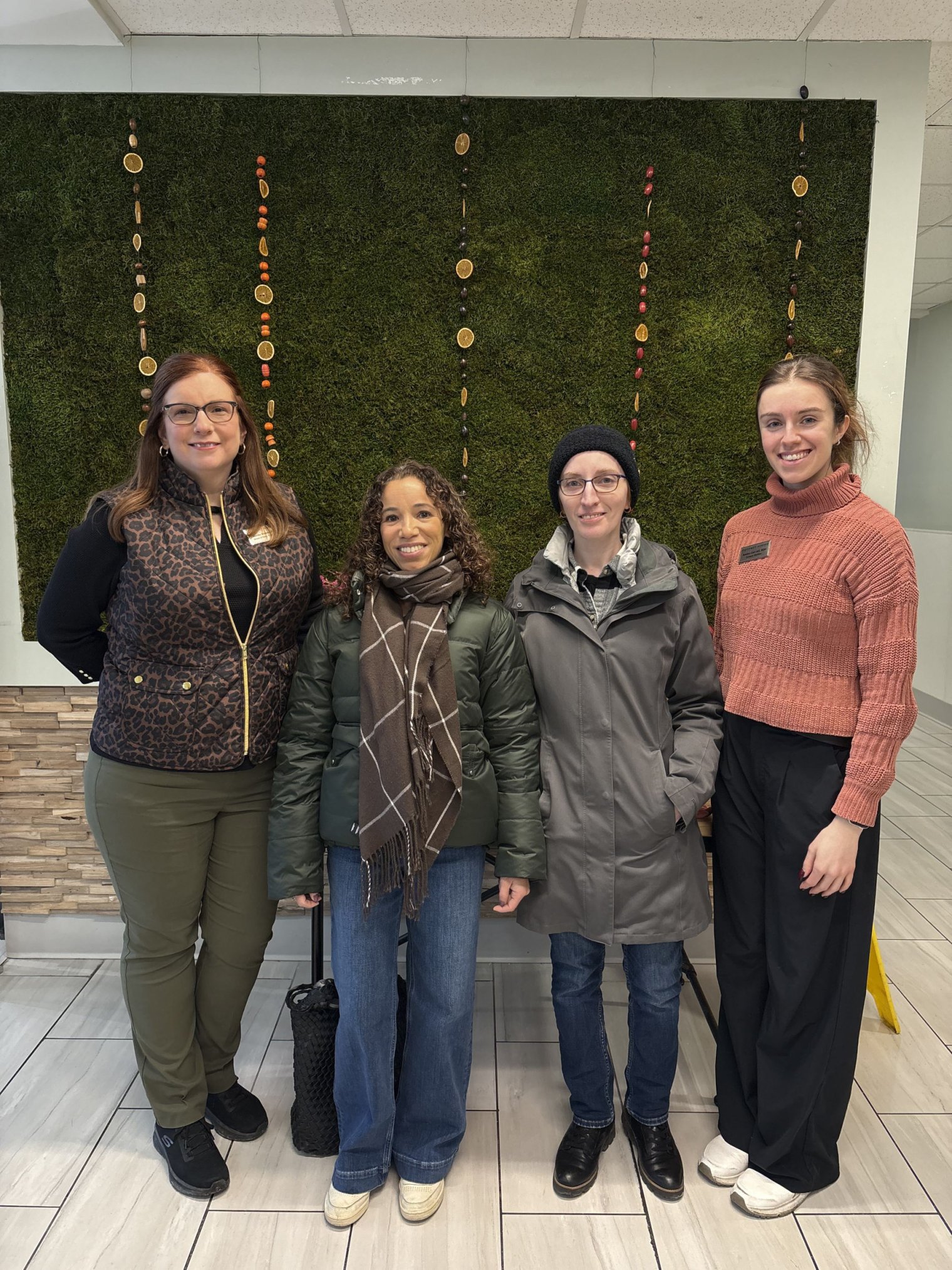 Photo of (left to right) Jennifer Bostedo, Michelle Bradley, Adeline Cochran, and Jessica Carr standing in front of a moss wall in Freeman Dining Hall.