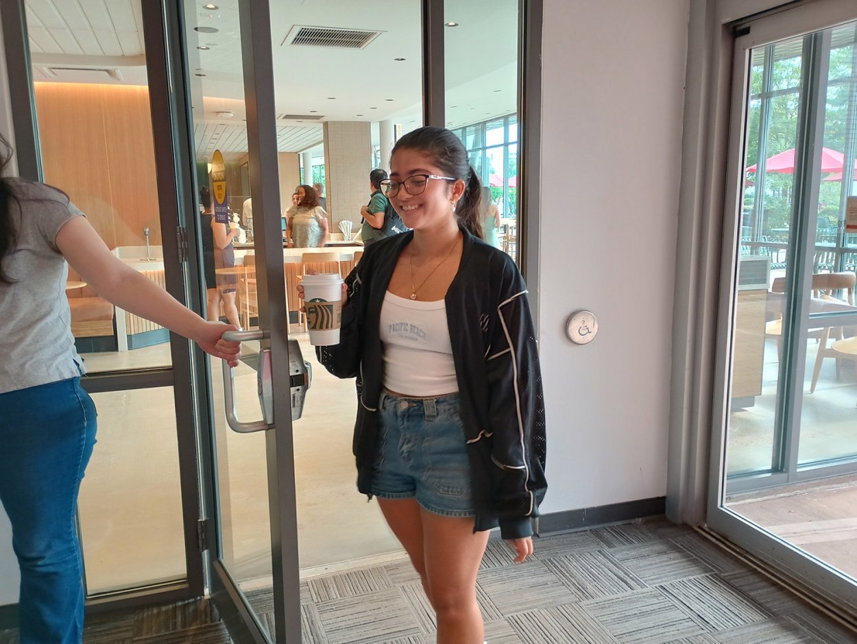 woman entering library from starbucks holding coffee