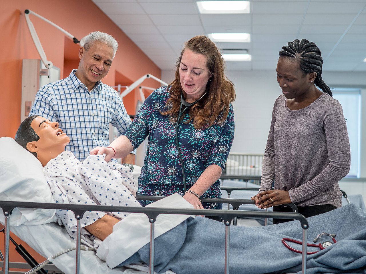 Students monitoring vitals on a patient care manikin.