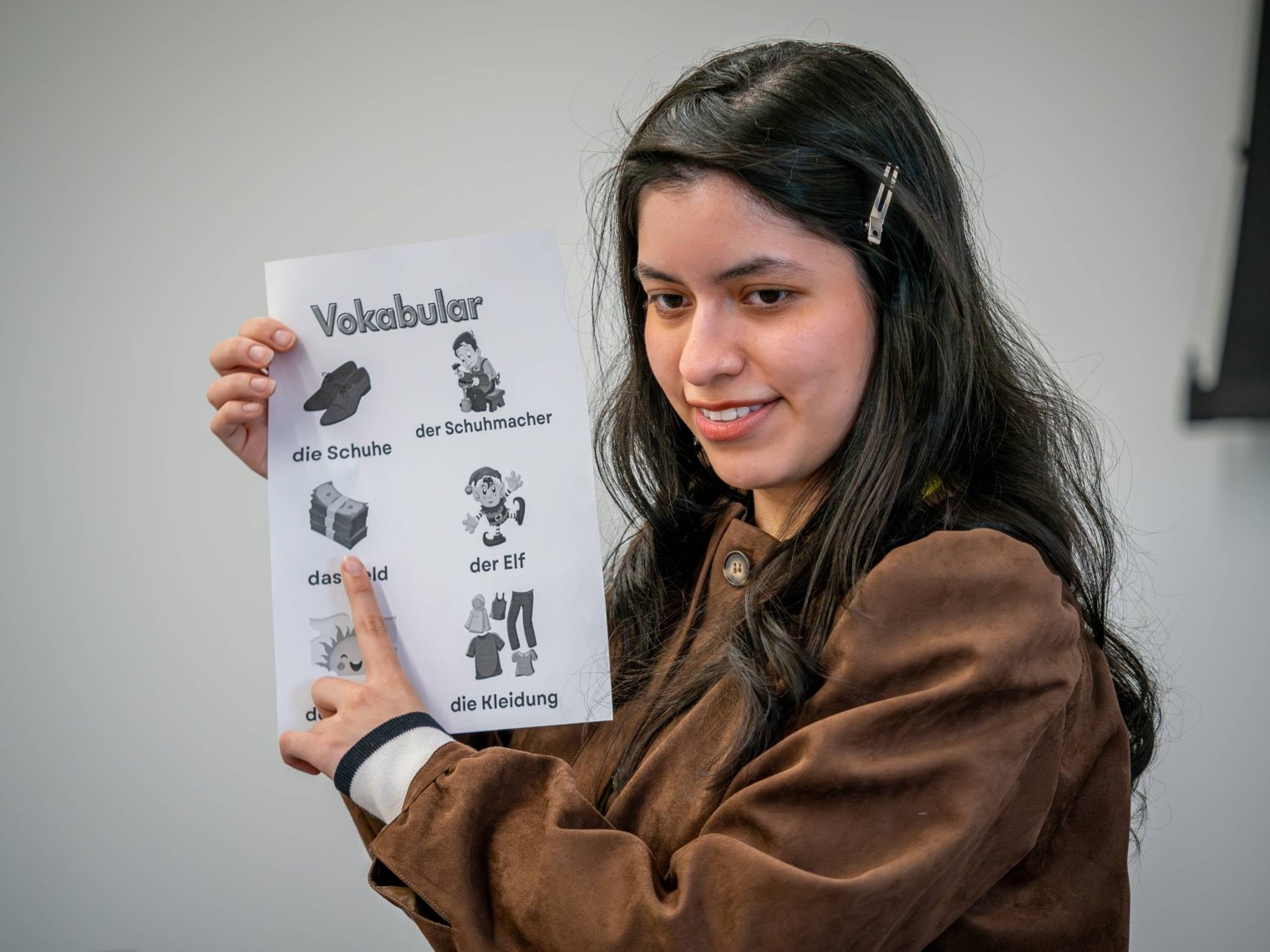 A woman holds up a paper with several German words written
