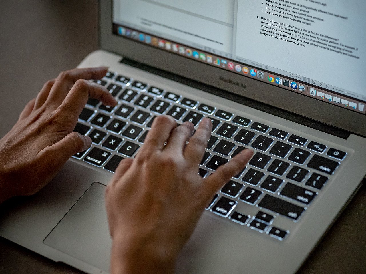 closeup of hands typing on macbook