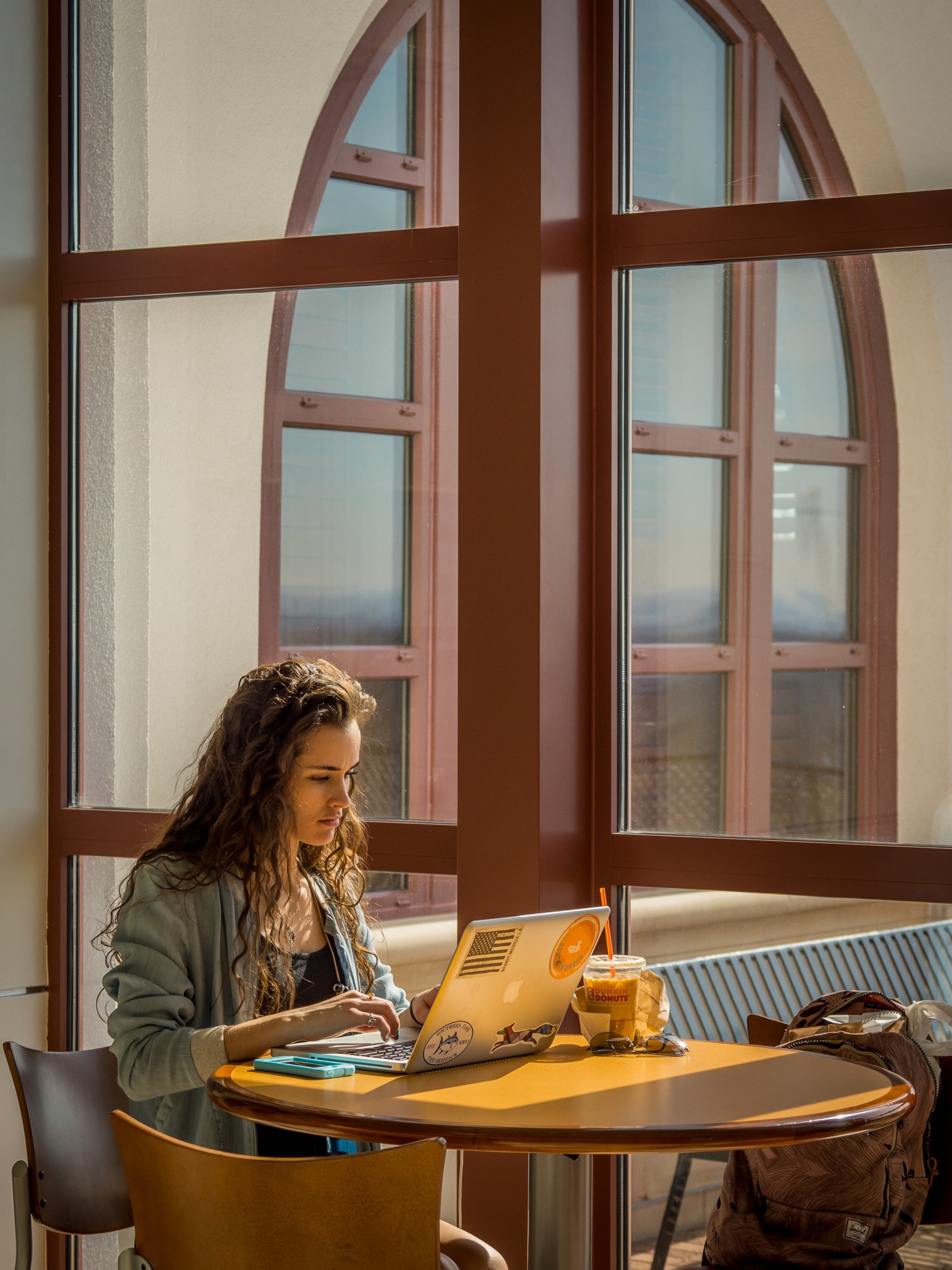 A student on her laptop sitting by a window.
