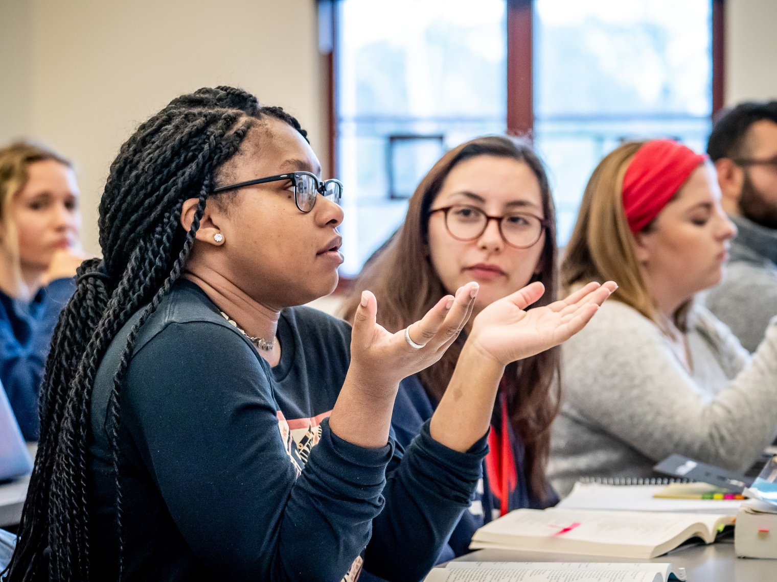 One female student speaking in a class as another looks at her