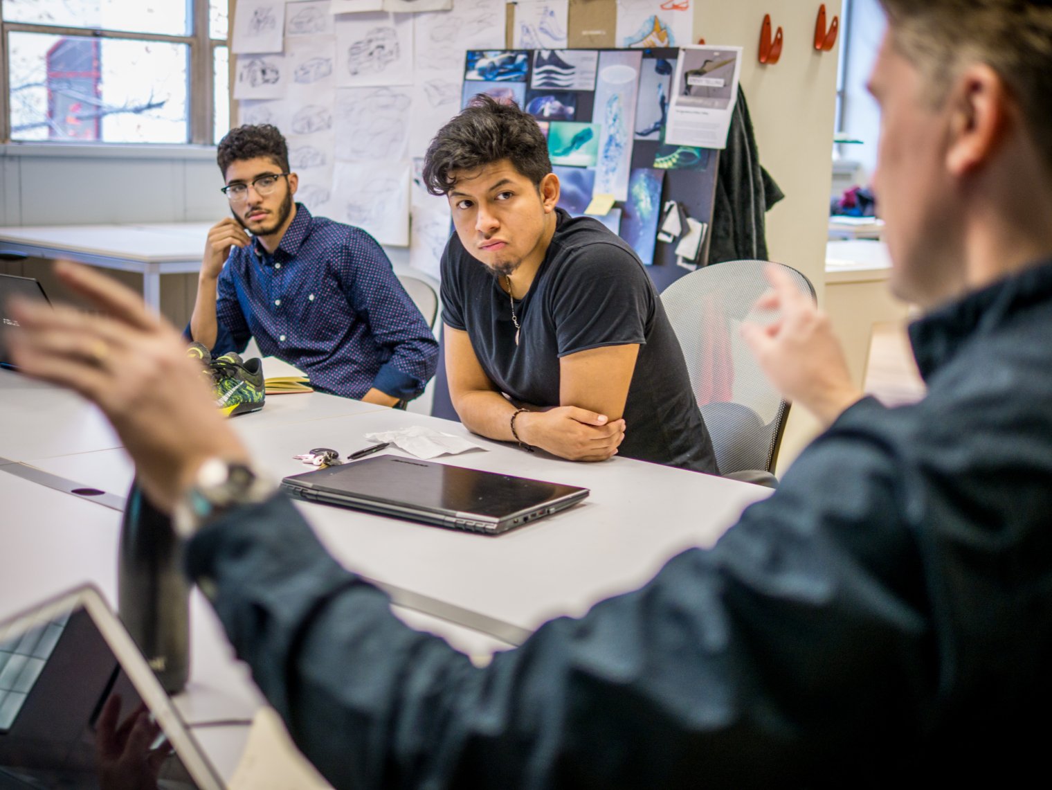 Two male students listening to their professor in a classroom
