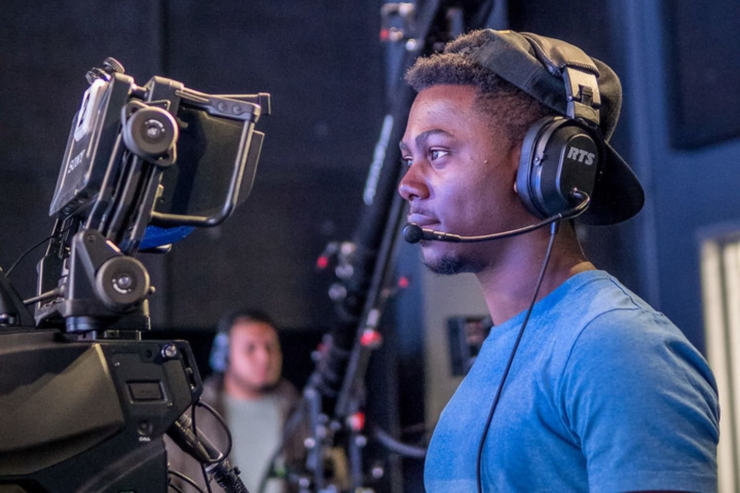 Student wearing a headset operates a camera in a newsroom.