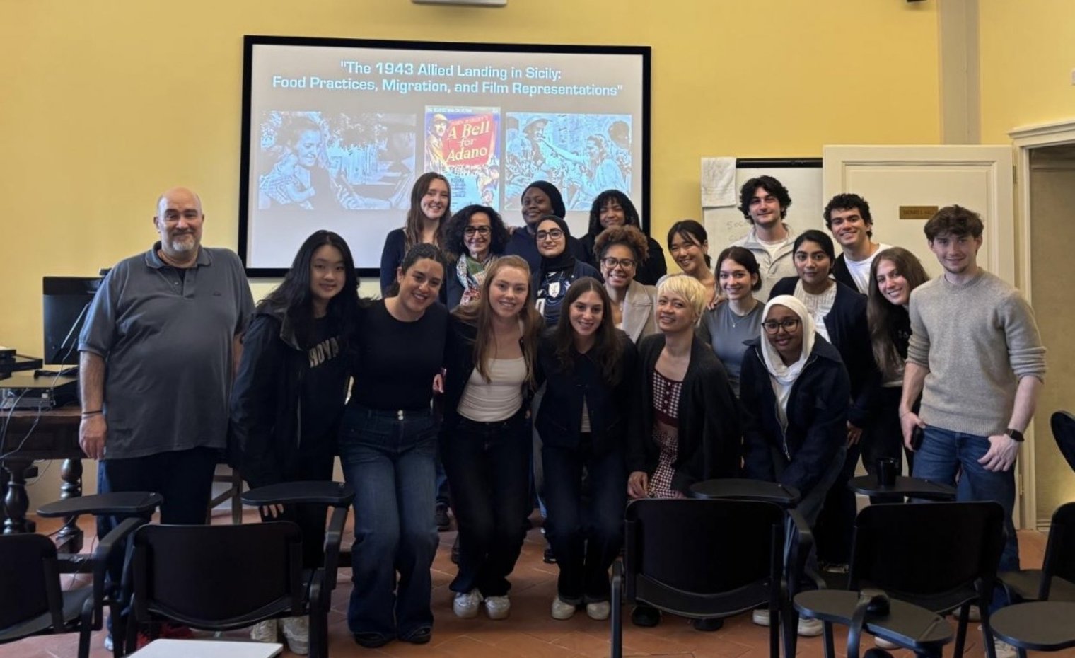 A group of people pose together in front of a projector screen