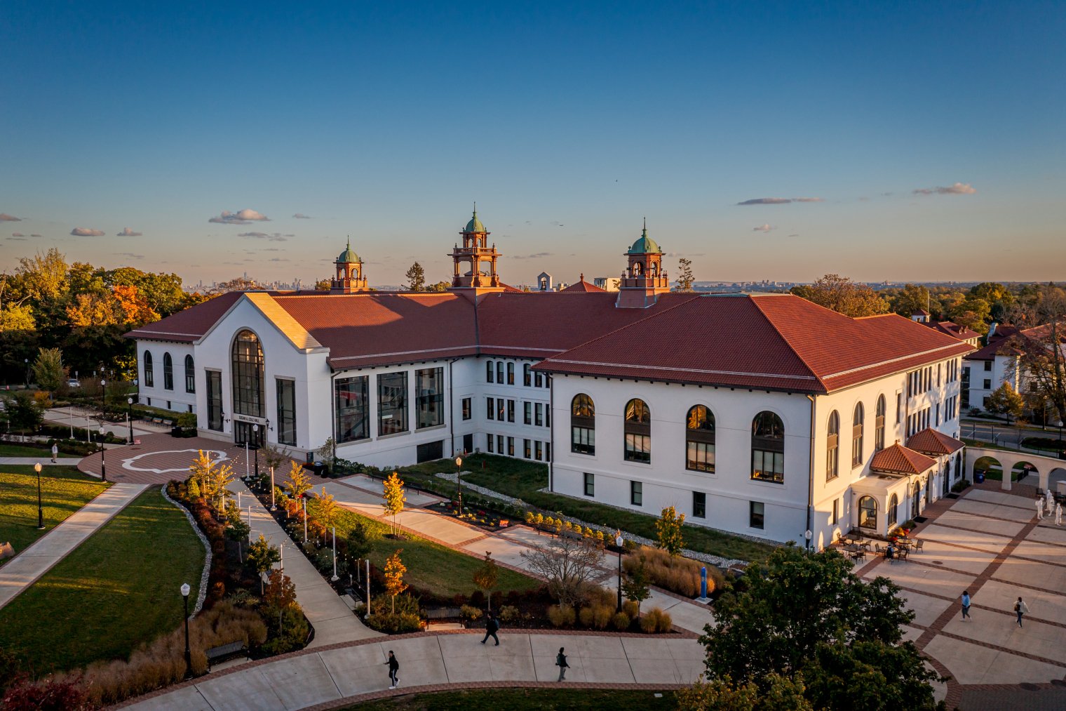 Aerial view of Cole Hall at dusk. People walk along pathway in front of building.