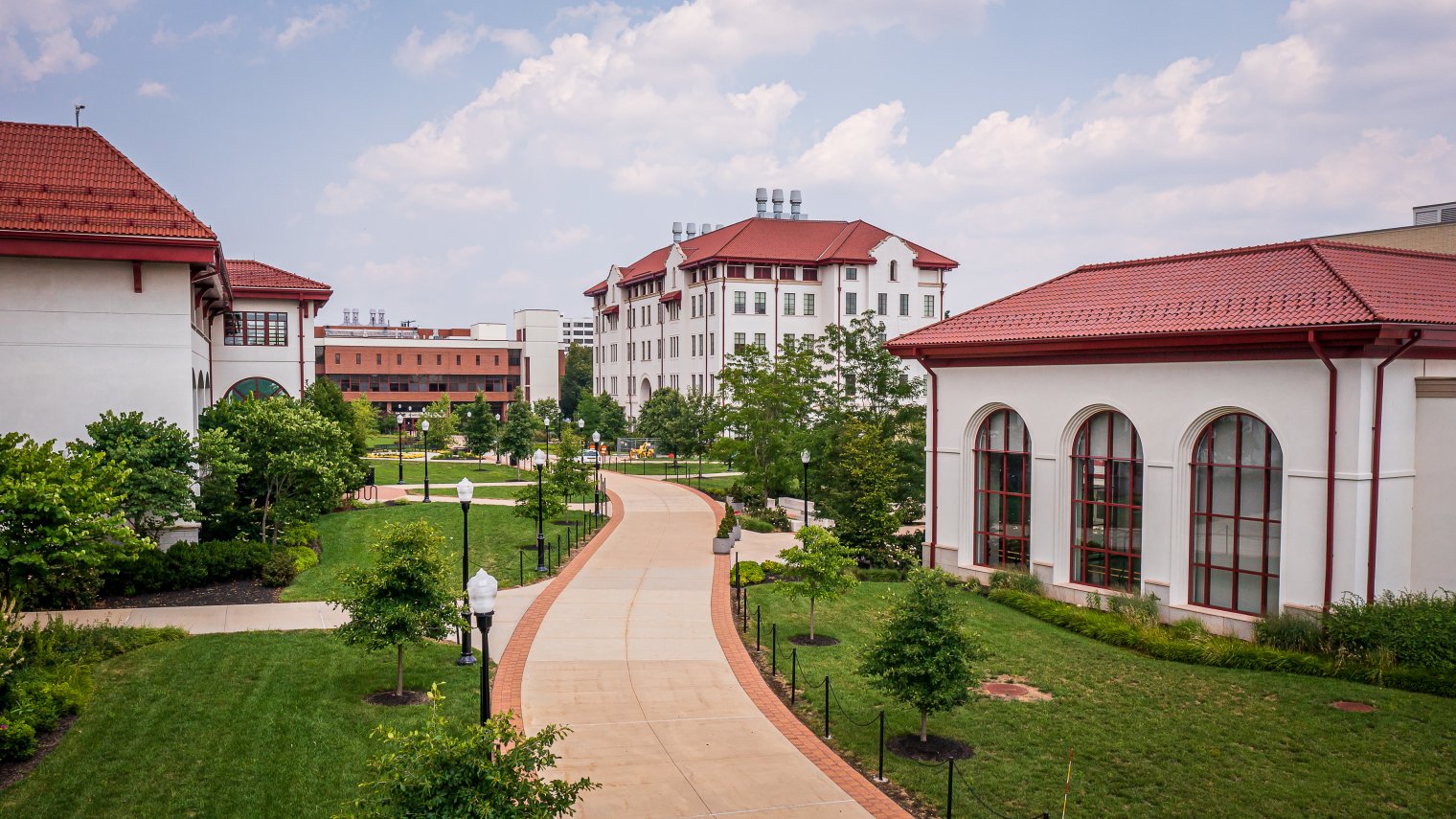 Pathway between several buildings on Montclair's main campus heading toward Richardson Hall. Green grass and trees are between the buildings and path.