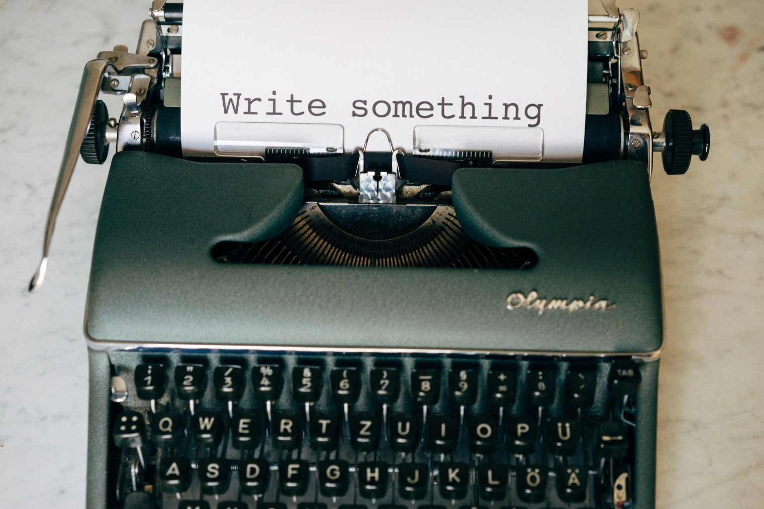 A manual typewriter with a page that says "Write something"