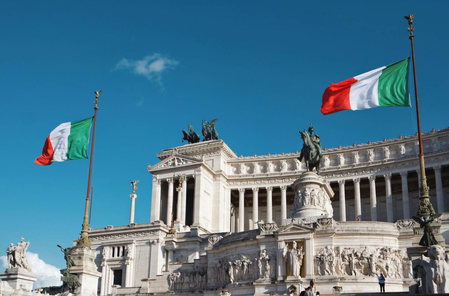 The Victor Emmanuel II Monument in Rome, Italy, with two Italian flags in front of the white marble monument