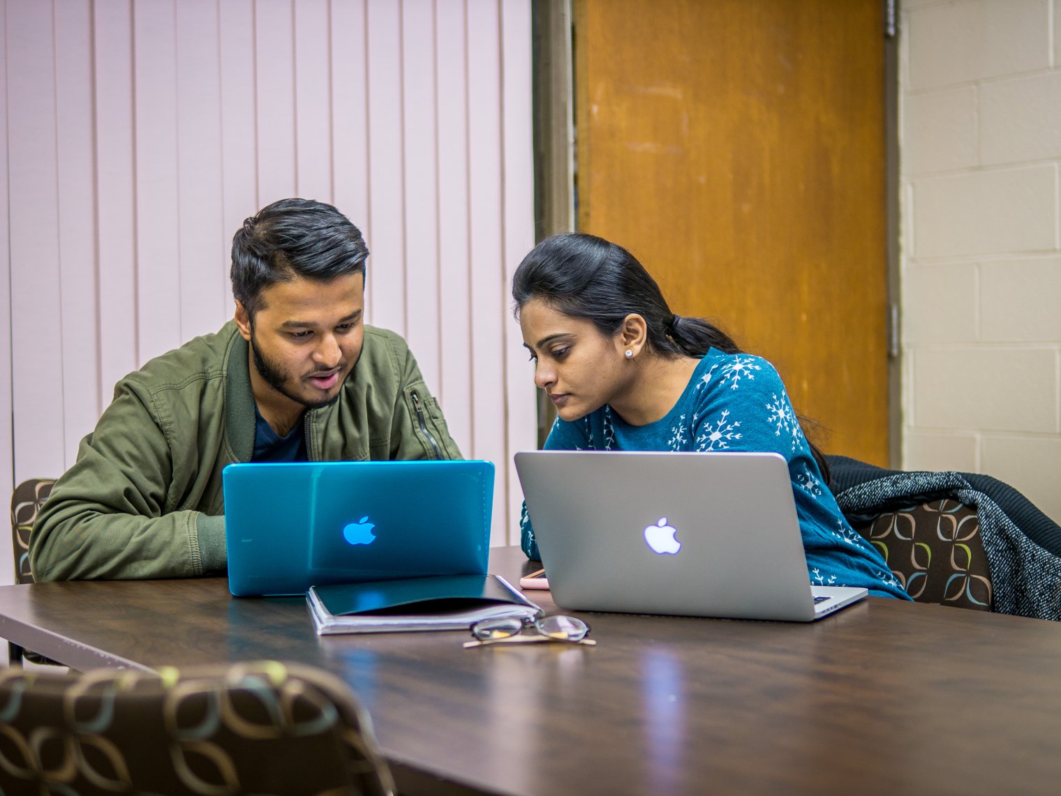 two students sit in front of laptops