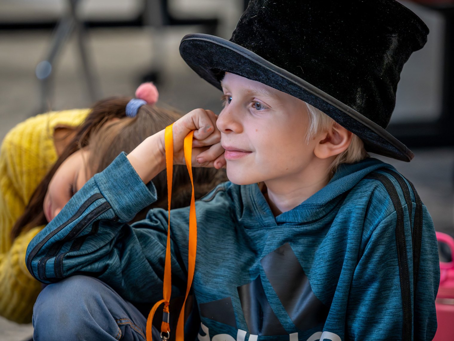 Young child wearing a top hat smiling.