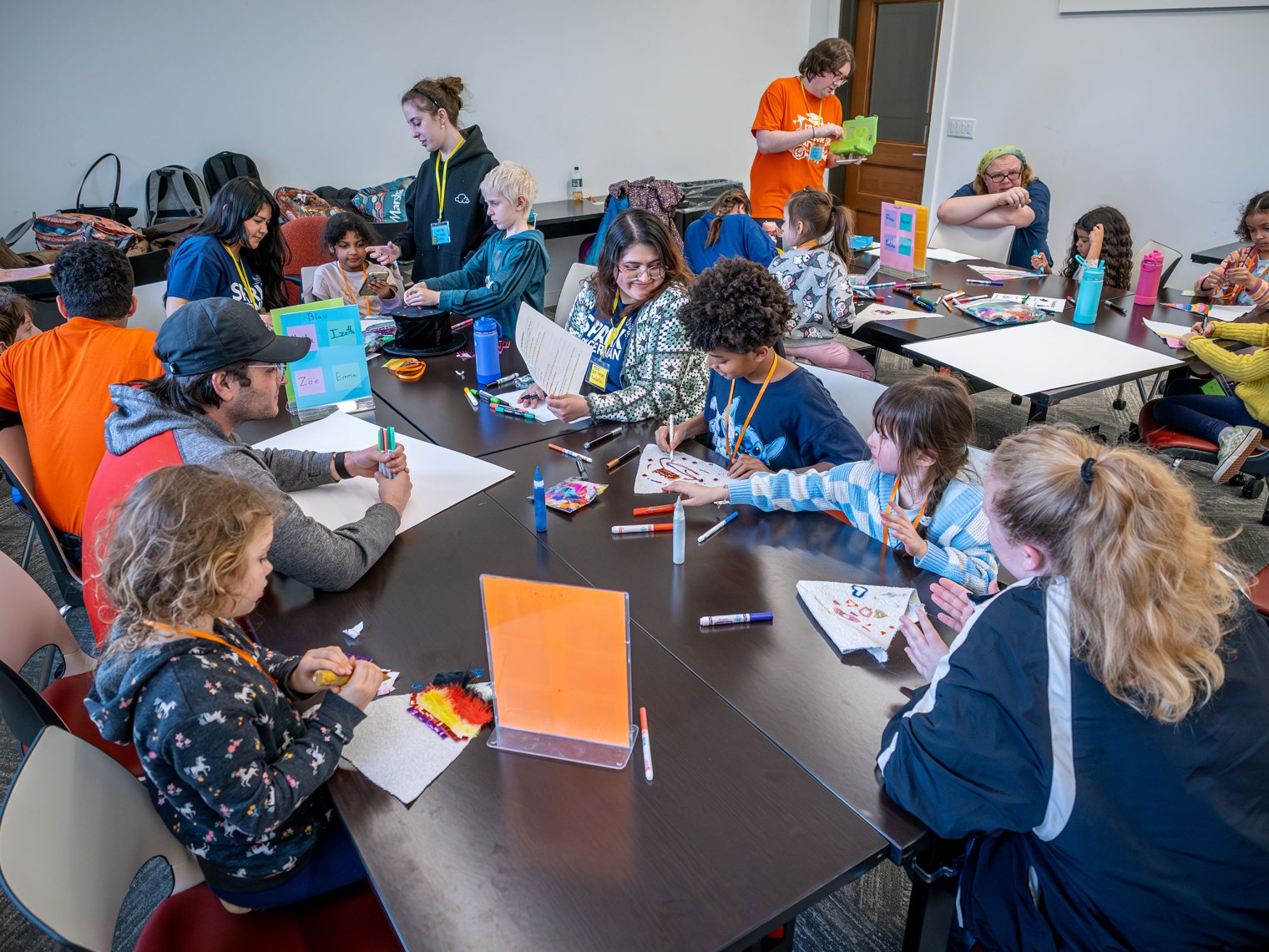 Students and adults sat around a large table doing arts and crafts