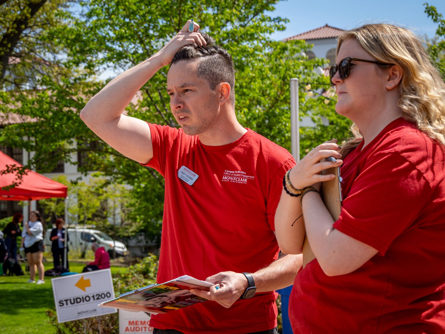 Casey Coleman and a student, Hannah Minor, stand side by side on the lawn, both holding clipboards as they look ahead thoughtfully, conferring about a checklist.