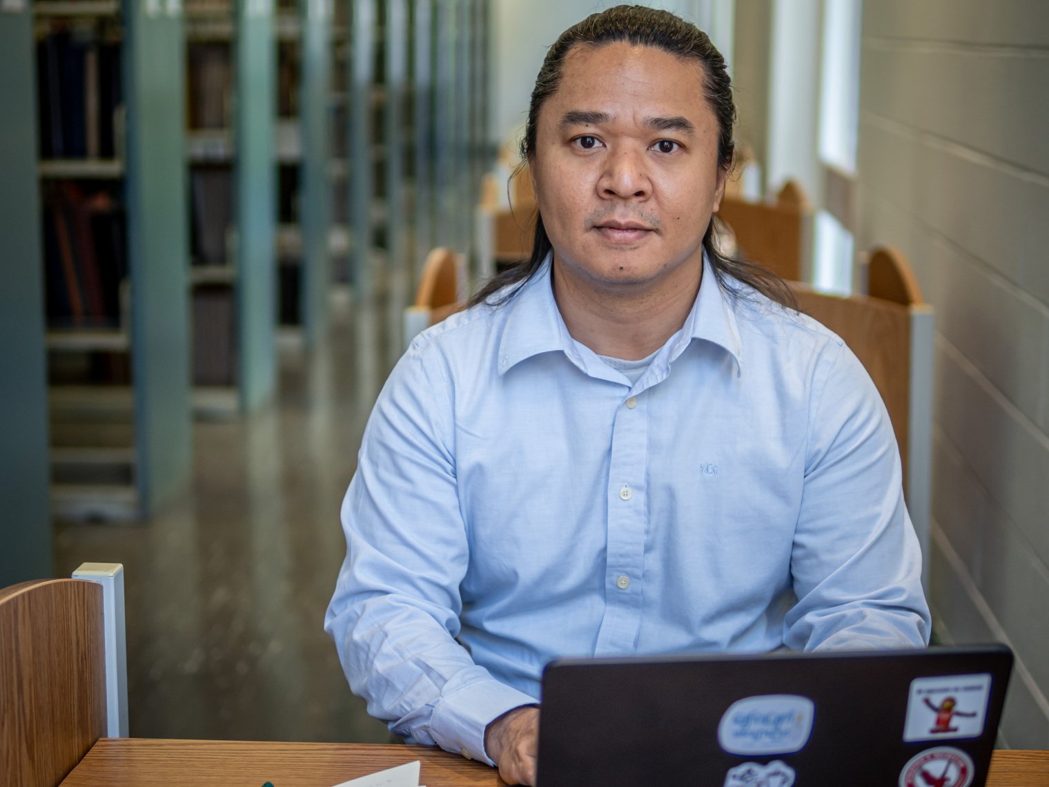 Kaung Hla Zan sits in at library desk with an open laptop in front of him.