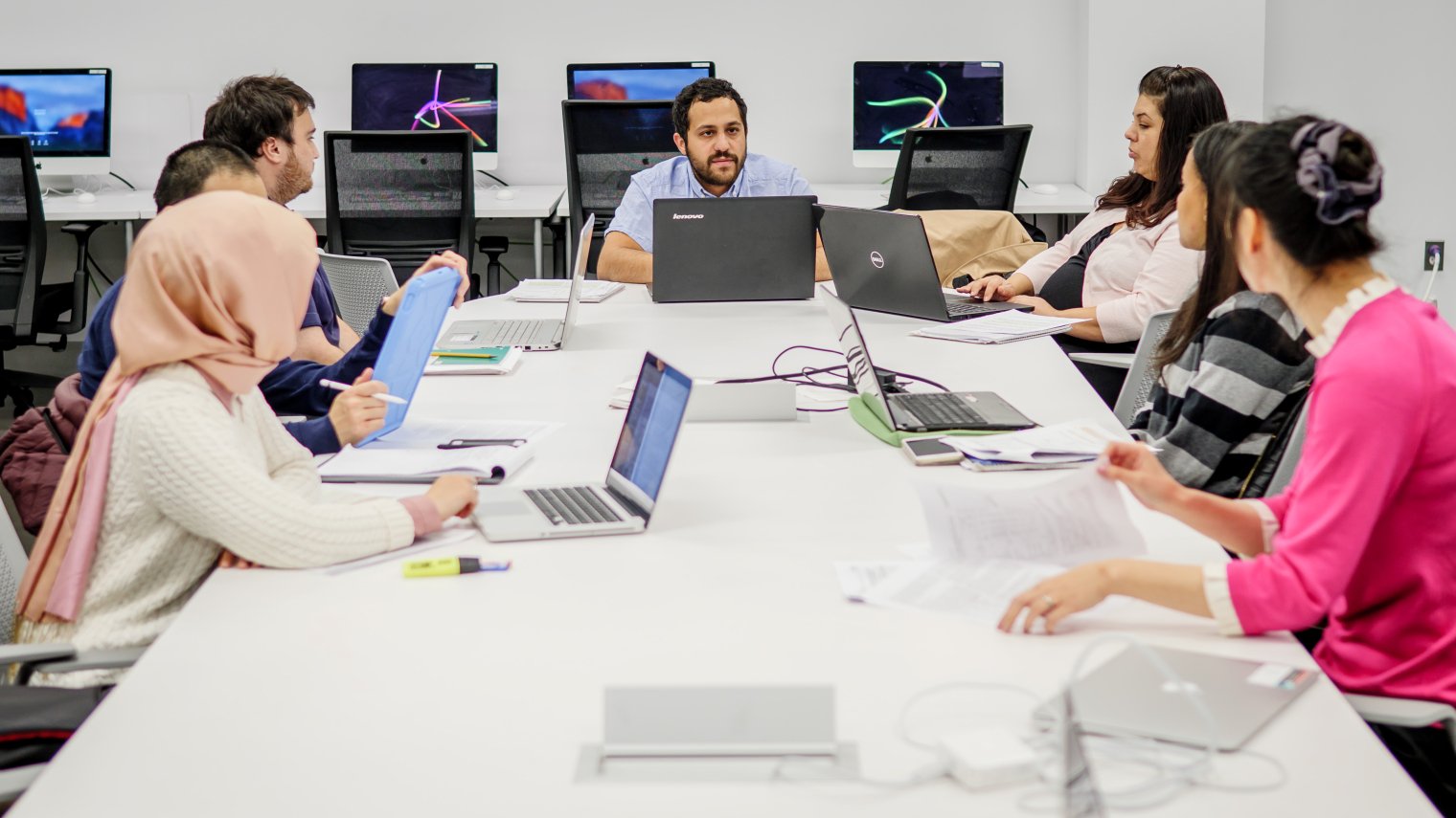 Students working on their computers at a long table.