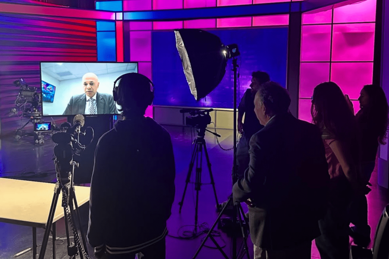 Students in Studio A interviewing a subject virtually with tv screen propped up in the center of the studio.