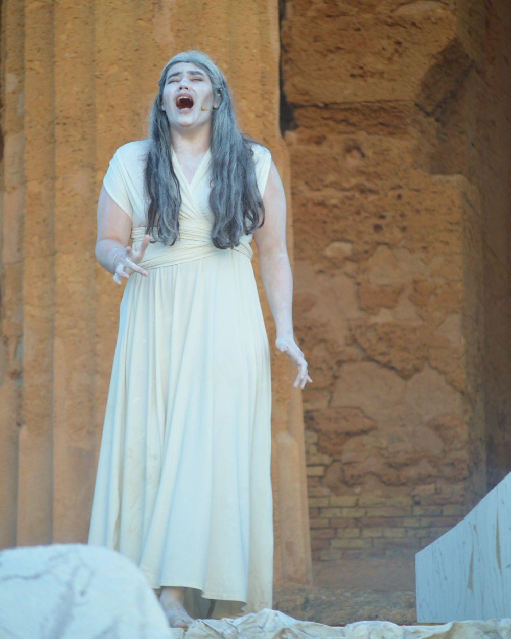 A woman wears an ancient Greek costume and performs on stage