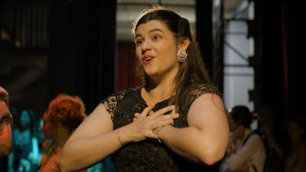 A woman in a black dress performs on stage