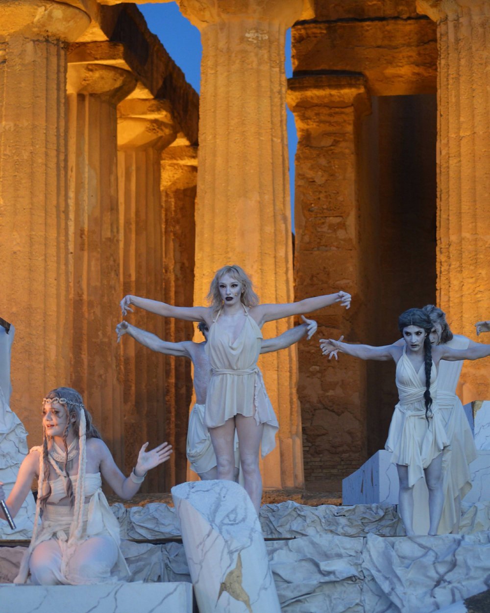 A woman wearing an ancient Greek costume performs on stage