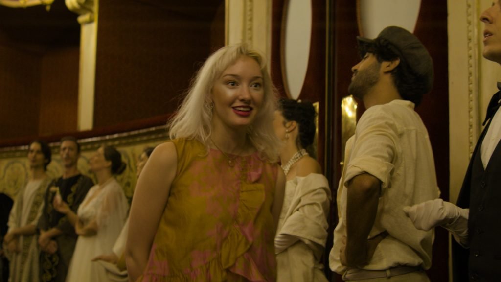 A woman wearing an ancient Greek costume performs on stage