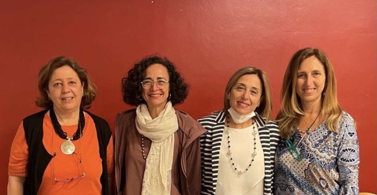 Teresa Fiore and other talk panelist pose for a photo with a red wall as backdrop